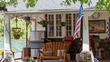 Een veranda met een houten Adirondack-stoel, een Amerikaanse vlag en een stenen muur.