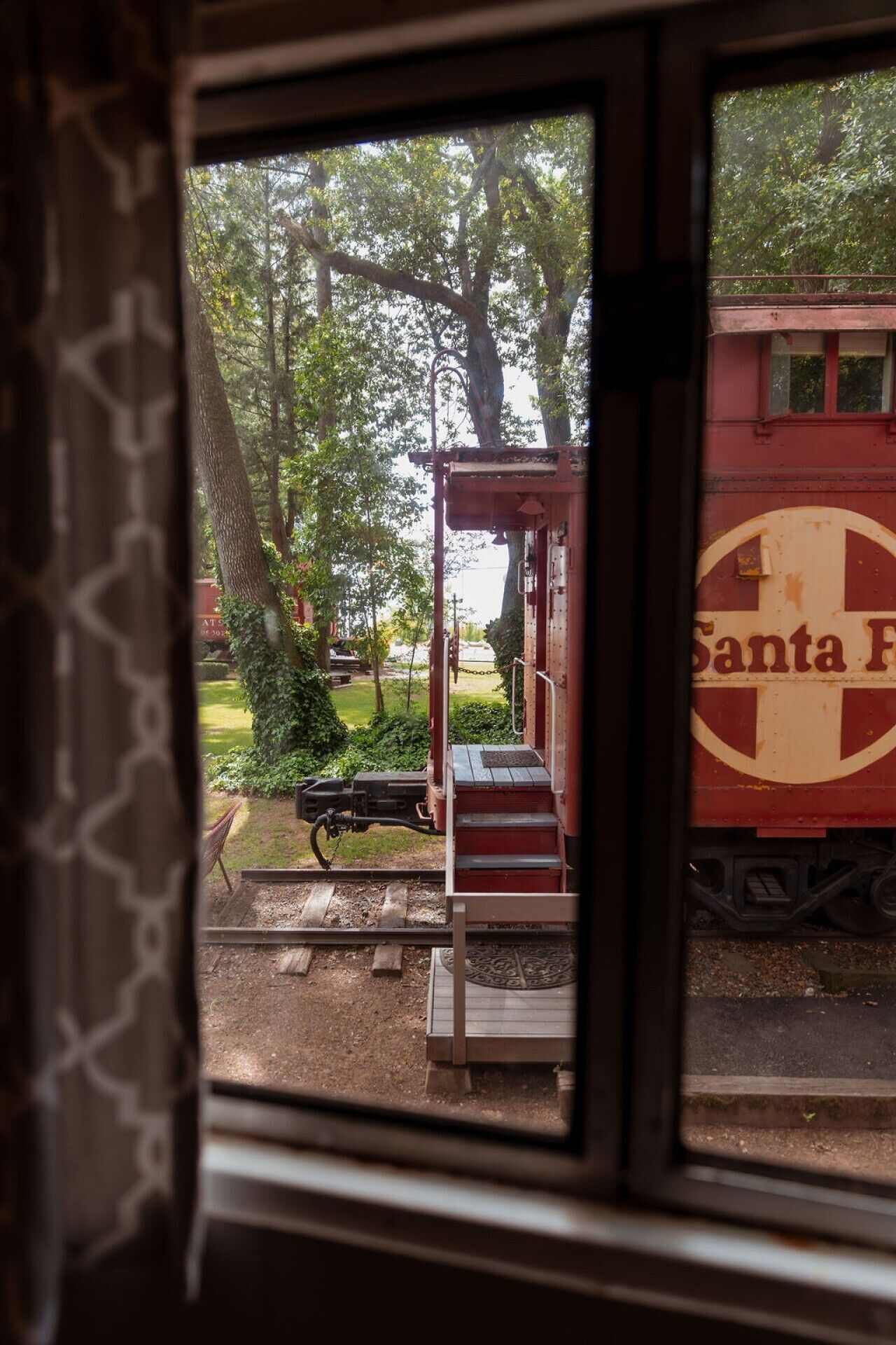 A window view of a train station platform with a red train marked 'Santa Fe' in the background.
