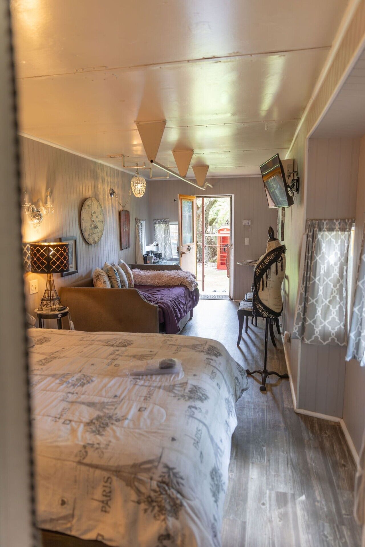 Een kamer met een bed, bureau, stoel, lamp, klok en raam.