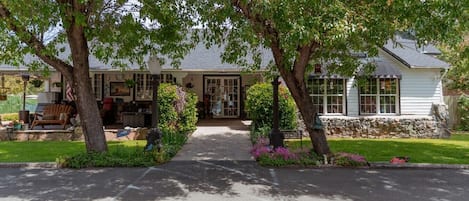 Ein zweistöckiges Haus mit Veranda, Steinunterbau und einem gepflegten Rasen.