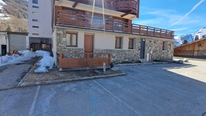 Un edificio a due piani con facciata in pietra, un balcone in legno e terreno innevato.