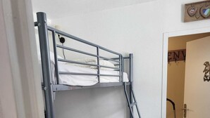 Un letto a castello con una scala, un comodino e una porta con un cartello.