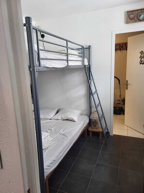 Ein Stockbett mit einer Leiter, ein kleiner Nachttisch und eine Tür mit einem Schild.