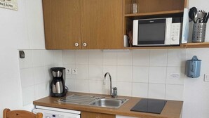 Una cucina compatta con mobili in legno, un forno a microonde, una macchina da caffè e un lavastoviglie.