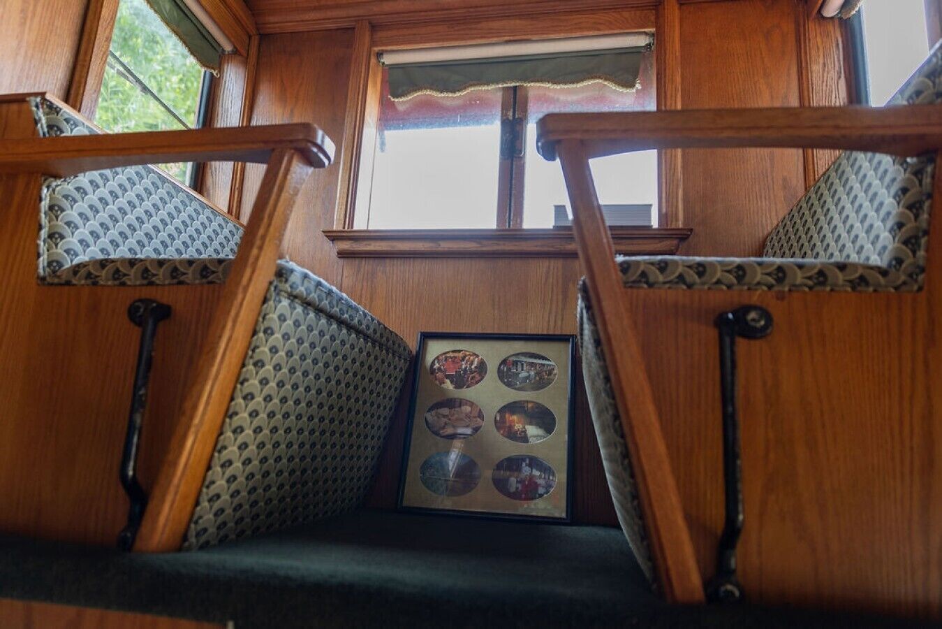 A wooden staircase with a patterned cushion and a framed picture of a cityscape.
