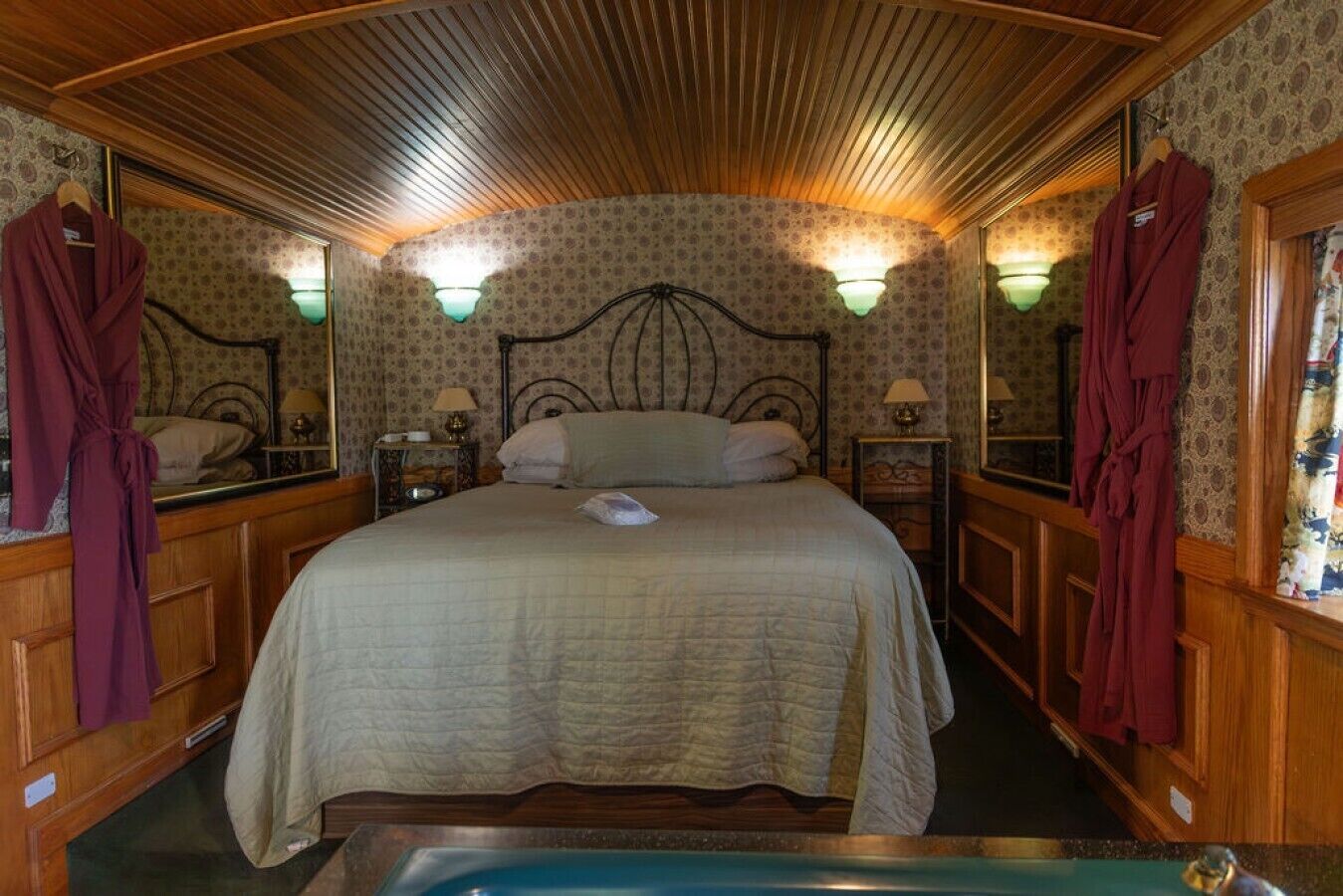 Ein Zimmer mit einem großen Bett, zwei Nachttischen, Wandleuchten und einem Spiegel.