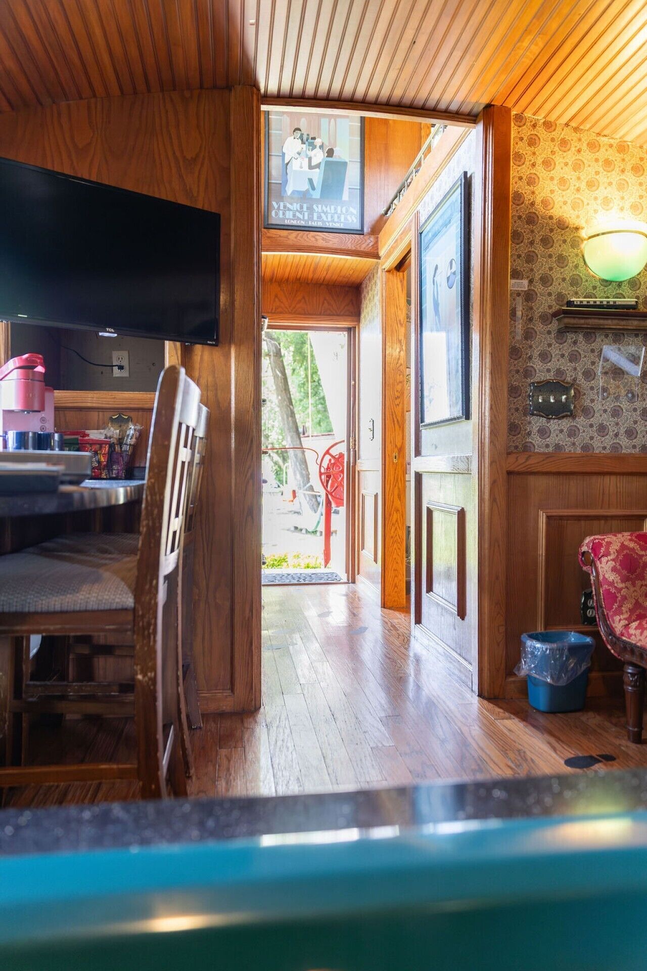 A wooden interior with a dining area, a television, and a door leading outside.