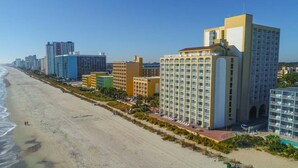 Un hotel frente al mar con varios pisos y una zona de piscina.