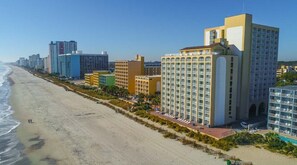 Ein Hotel an der Küste mit mehreren Etagen, einer Strandlage und einem Poolbereich.