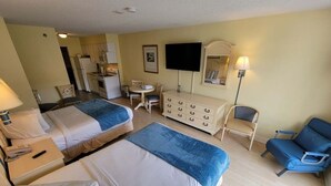 Habitación de hotel con dos camas, un aparador, un televisor y un escritorio con una silla.