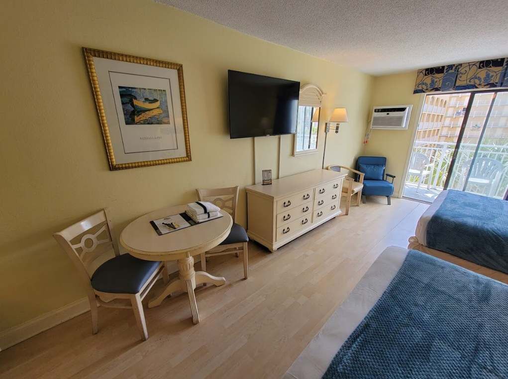Une chambre d’hôtel comprenant un lit, un bureau avec une chaise, une télévision, une commode et une fenêtre donnant sur un paysage agréable.