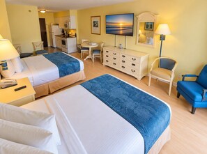 A hotel room with two beds, a dining table, a TV, a dresser, and a chair. - The Coastal SM | Fifty Oh Four Oh Three (Myrtle Beach)