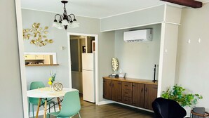 Un espacio de estar moderno con comedor, una silla negra, piso de madera y techo con vigas a la vista.