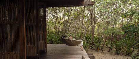 A wooden deck leading into a lush garden with a hammock.