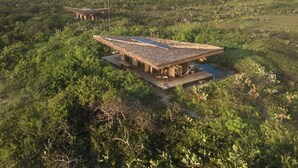 A large, open-air structure with a flat roof, surrounded by dense vegetation. - Casitas by the Sea (Villa de Tututepec de Melchor Ocampo)