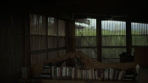 A dimly lit room with a wooden desk, books, and a large window with metal bars. - Casitas by the Sea (Villa de Tututepec de Melchor Ocampo)