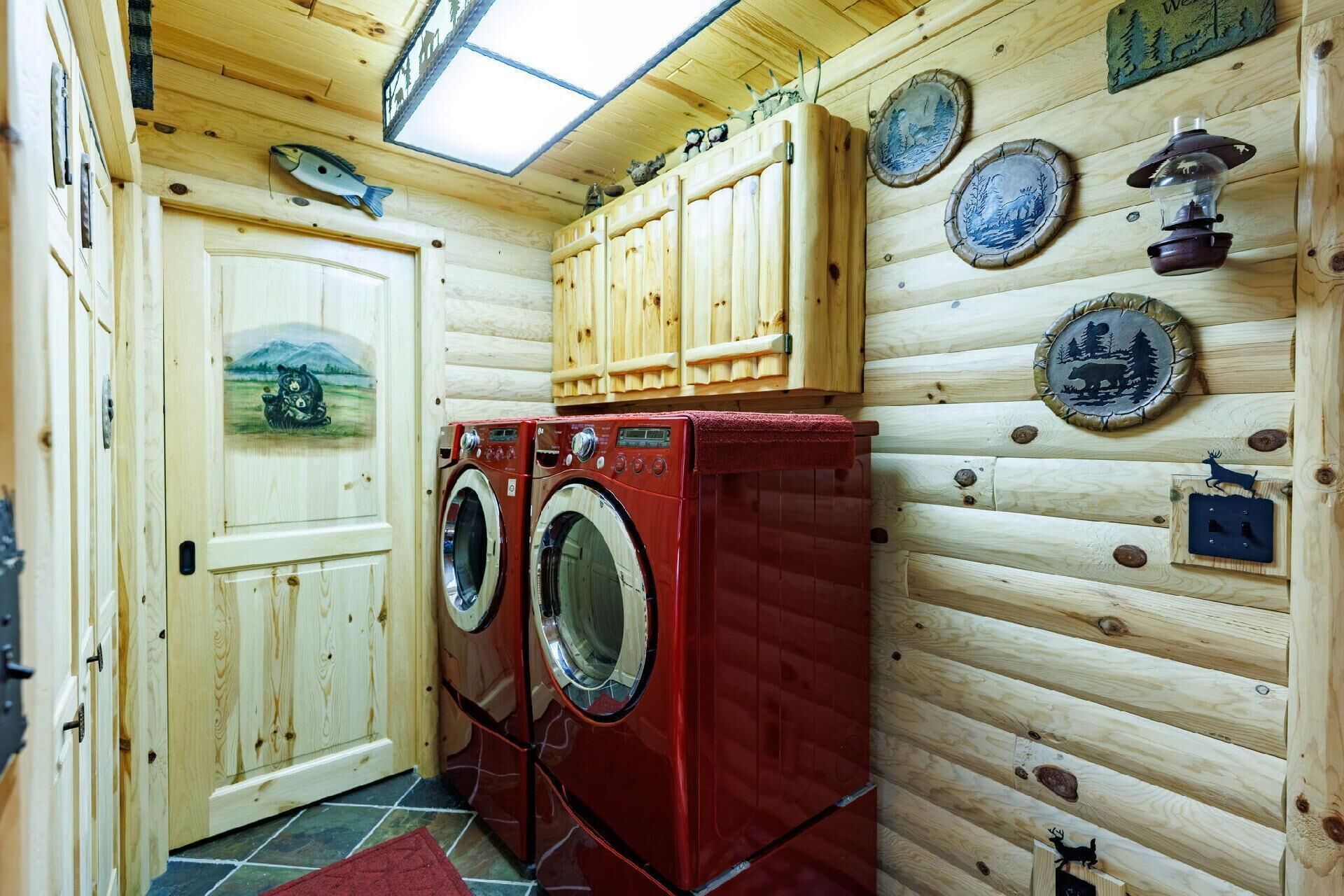 A wooden cabin interior with a washing machine, wooden cabinets, and decorative plates.