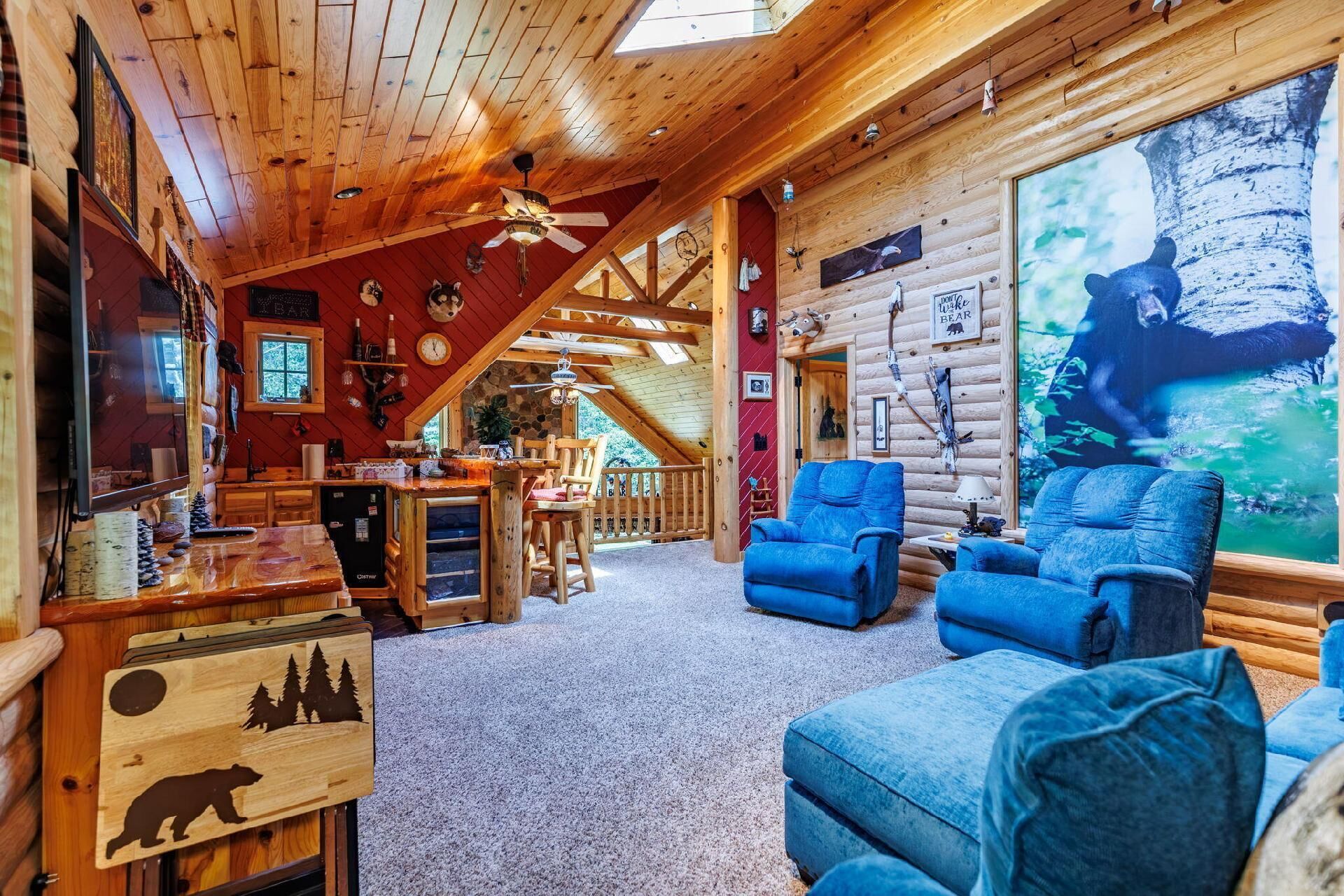 Ein Holzblockhaus-Interieur mit Essbereich, blau gepolsterten Sitzmöbeln und einem Wandgemälde mit Bärenmotiven.