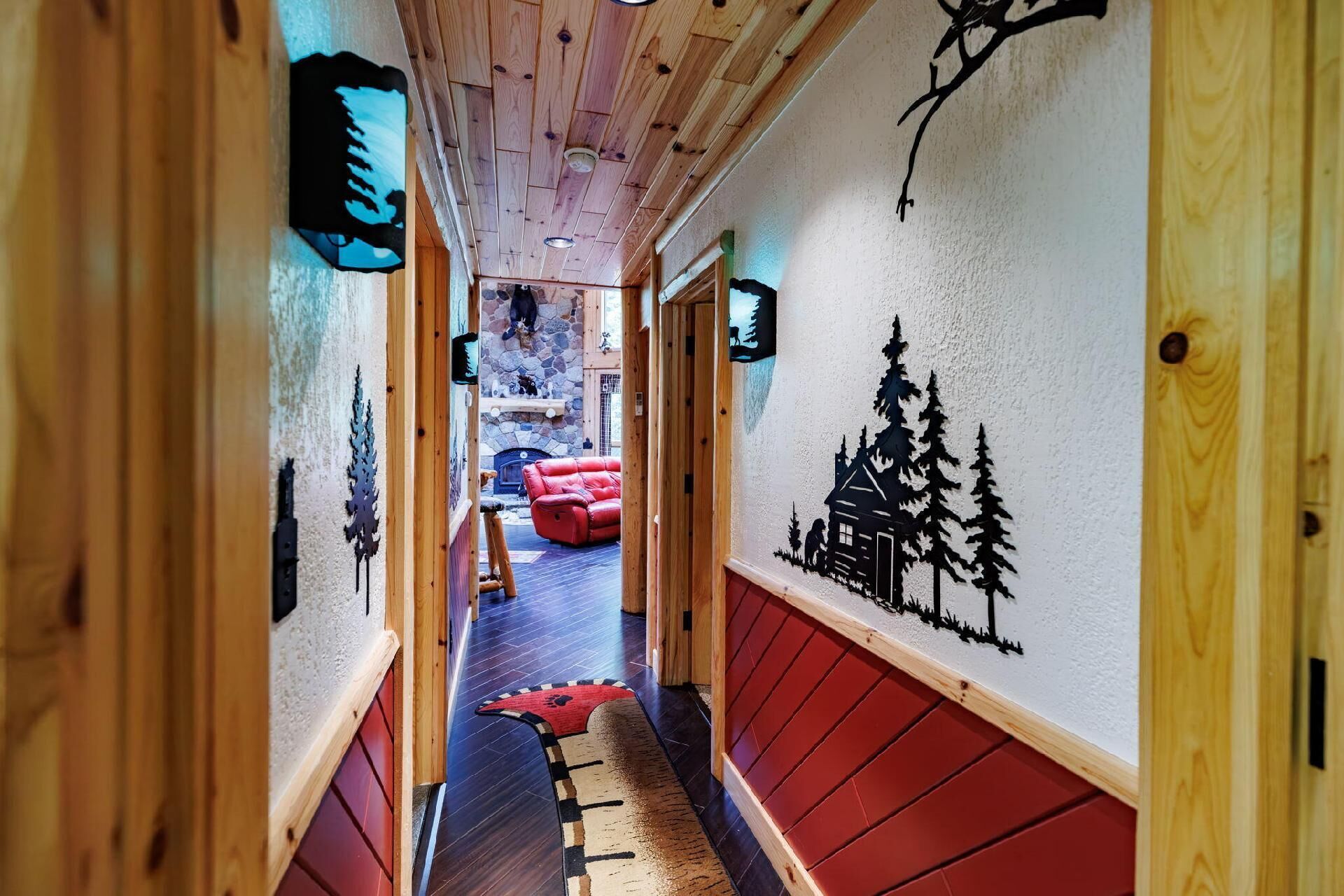 Un couloir en bois avec une cheminée, des sièges rouges et des œuvres d’art murales.