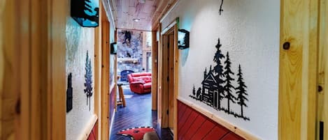 Un couloir en bois avec une cheminée, des sièges rouges et des œuvres d’art murales.