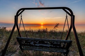A swing set overlooking a sunset over a body of water. - Bear-Themed Lodge / Sleeps 10 / Private Beach (Millersburg)