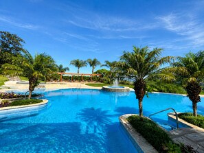 Una gran piscina al aire libre con palmeras y un pabellón.