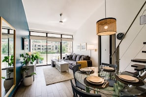 A modern living room with a glass dining table, sofa, and large windows. - Modern Lakeview Penthouse: Pool/Gym/Restaurant (Río Oro)