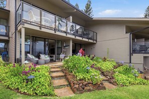 Une maison moderne dotée d’un balcon, d’un espace salon extérieur et d’un jardin agrémenté de pas japonais.