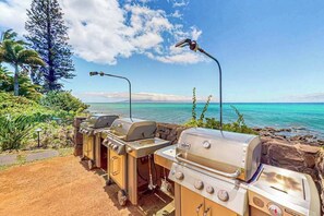 A barbecue setup with a view of the ocean and a clear sky. - Mahina Surf 123 & 124 (Lahaina)
