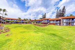 A hotel with multiple-story buildings, a well-maintained lawn, and a clear sky. - Mahina Surf 123 & 124 (Lahaina)