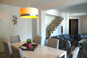 A modern living room with a dining area, a staircase with patterned tiles, and a large pendant light. - House in the center of town near the river with 3 bedrooms and air conditioning (Alcoutim)