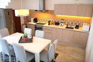 Eine moderne Küche mit Essbereich, ausgestattet mit Herd, Kaffeemaschine, Toaster und Spüle.