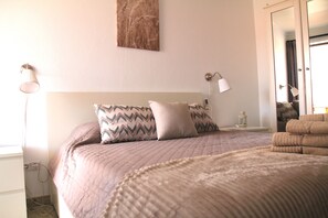 Ein Schlafzimmer mit einem Bett, Kissen, einem Nachttisch, einer Lampe und einem Wandbild.