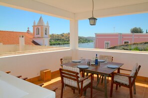 A dining area with a table set for four, overlooking a river and buildings.