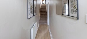 A narrow hallway with a carpeted staircase leading to a landing.