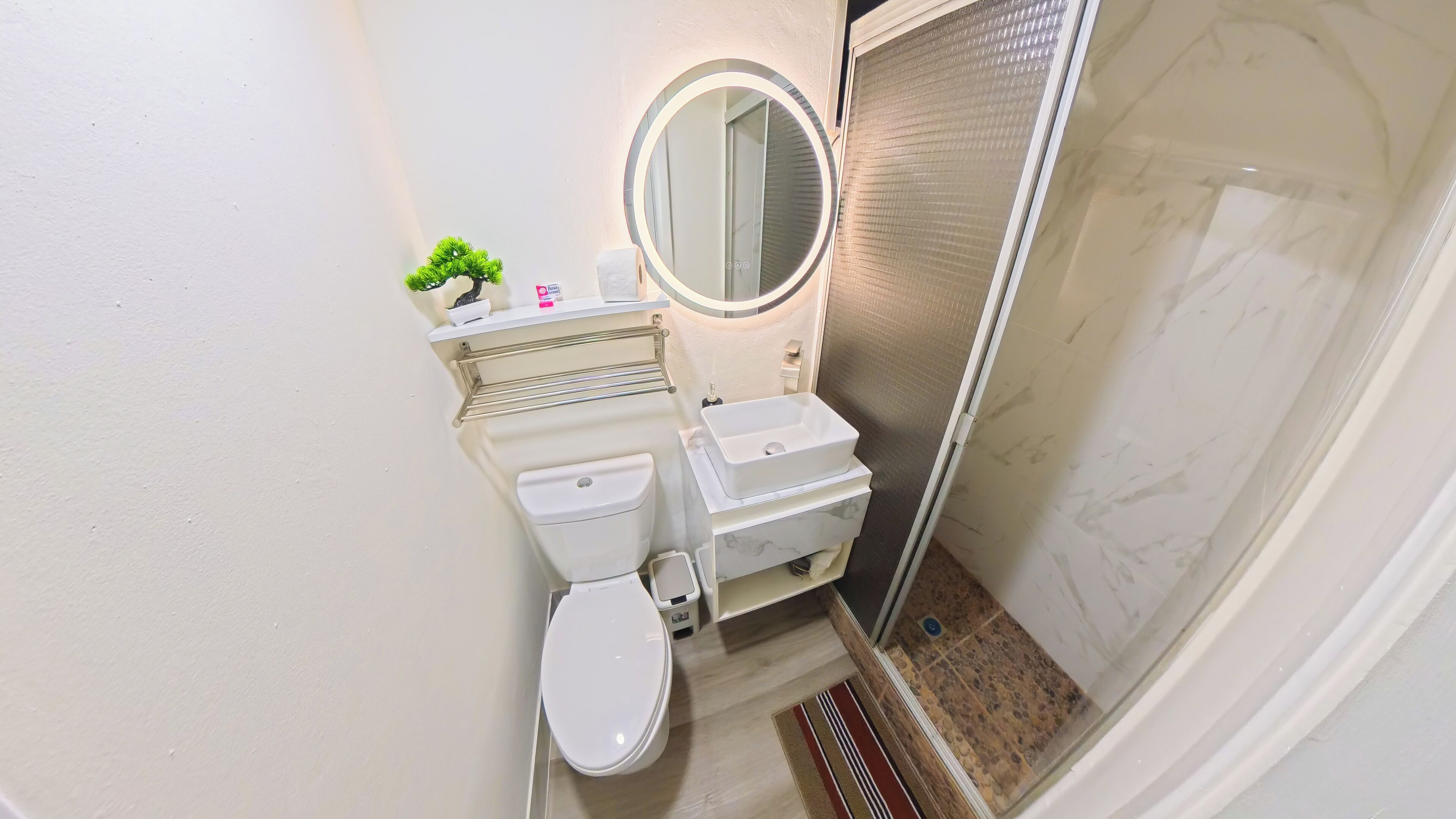 A compact bathroom with a toilet, sink, and a small mirror.