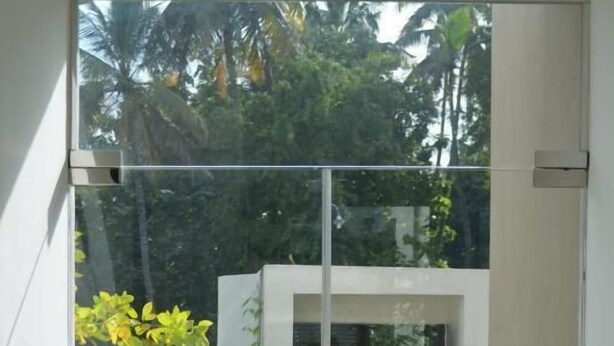 A glass door leading to a courtyard with a small building, potted plants, and a stone pathway. - Silina Airport Residence & Transit Hotel (Katunayake)