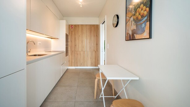 Eine moderne Küche mit weißen Schränken, einer Edelstahl-Spüle und einer Holztür.