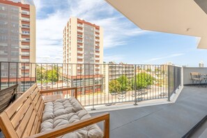 A balcony with a wooden bench, a metal railing, and a view of a parking lot and buildings. - GuestReady-Modern Retreat with Balcony Views (Lisbon)