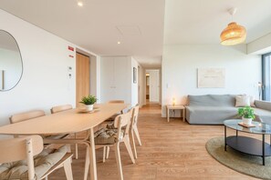 A modern living space with a dining area, a sofa, and a coffee table. - GuestReady-Modern Retreat with Balcony Views (Lisbon)