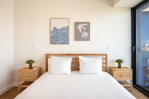 A bedroom with a large bed, two nightstands, and two wall-mounted artworks. - GuestReady-Modern Retreat with Balcony Views (Lisbon)