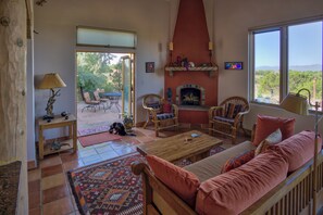 Un salon chaleureux avec une cheminée, des sièges confortables et une vue sur l’extérieur.