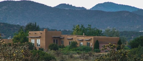 Un edificio de estilo desértico con varias habitaciones y techo plano, rodeado de cactus y arbustos.