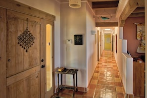 A hallway with wooden doors, a small table with items on it, and a tiled floor. - Tranquil 2-bedroom house perfect for a relaxing Santa Fe getaway (Santa Fe)