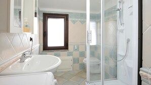 Een badkamer met een douche, toilet en wastafel.