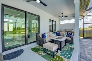 Un espacio exterior moderno con puerta de vidrio que da a un patio, un conjunto de sofás y una mesa de comedor.