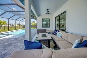 Un patio techado al aire libre con piscina, un sofá y una mesa.