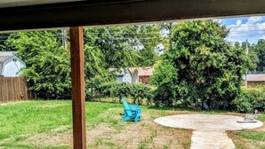A backyard with a concrete patio, a wooden post, and a blue chair. - The Rock House | Walk to OSU (Stillwater)
