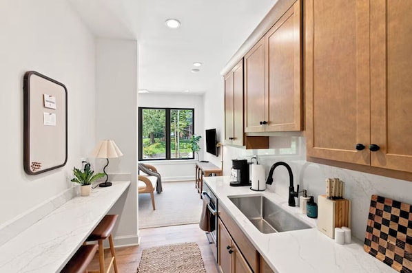 A modern kitchen with wooden cabinets, a marble countertop, and a built-in oven.