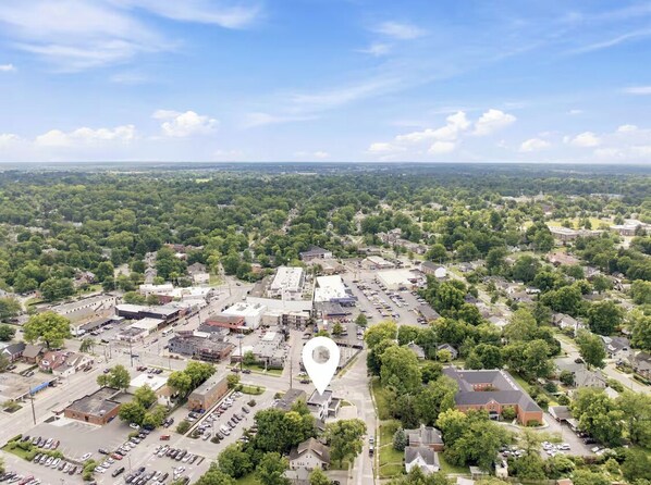 An aerial view of a town with a central commercial area, surrounded by residential zones and greenery.
